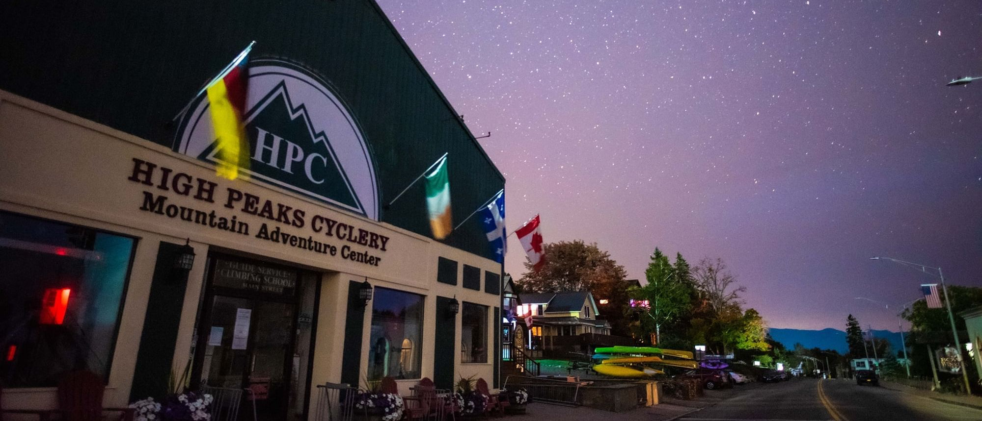 Storefront with 'High Peaks Cyclery' under a starry night sky